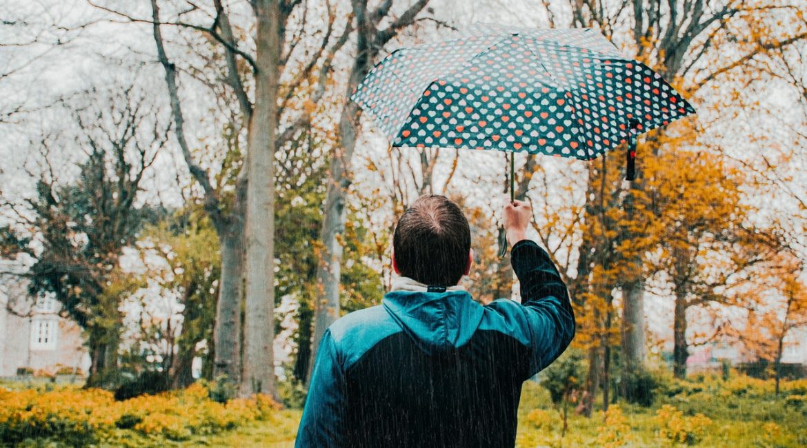 Mand står under paraply i natur